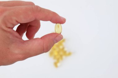 El beyaz arka plan üzerinde bir omega 3 hap tutarak