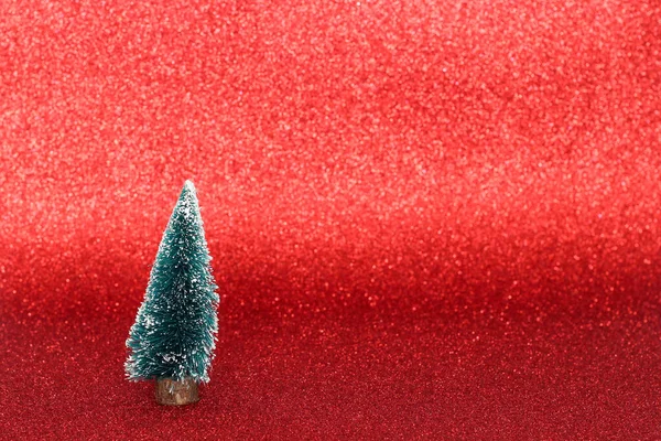 Small christmas tree decorations on glossy red background — Stock Photo, Image