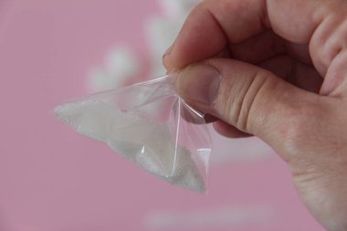 Elinde bir paket şeker olan bir adamın eli. Pembe arka plandaki uyuşturucu gibi.