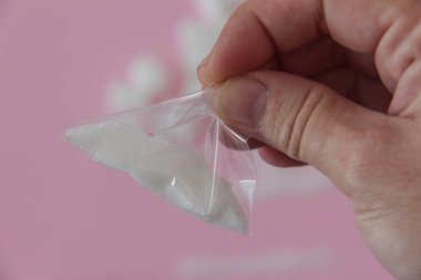 Elinde bir paket şeker olan bir adamın eli. Pembe arka plandaki uyuşturucu gibi.