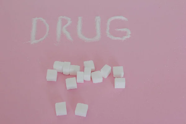 Drug written with sugar cubes on pink background — Stock Photo, Image