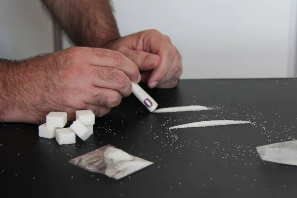 Un hombre con una mesa con azúcar blanca, azúcar como una droga . —  Fotos de Stock