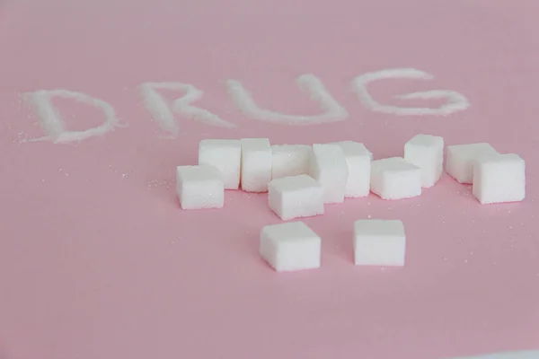 La parola droga scritto con cubetti di zucchero su sfondo rosa — Foto Stock