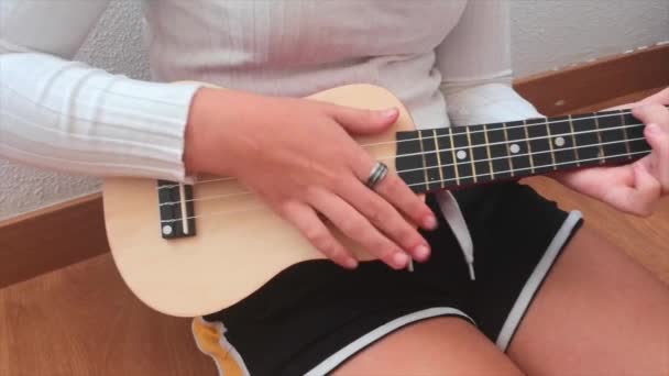 女孩弹奏口琴 坐在家里的地板上 — 图库视频影像