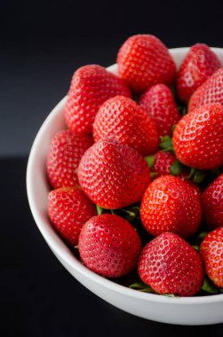 Siyah arka plan ile bir fincan güzel kırmızı çilek