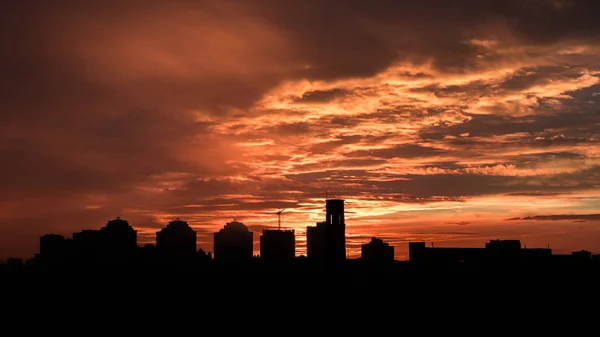 Sunset. Orange sky in the clouds. Silhouette of buildings.