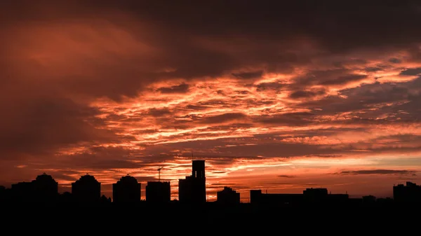 Sunset. Orange sky in the clouds. Silhouette of buildings.