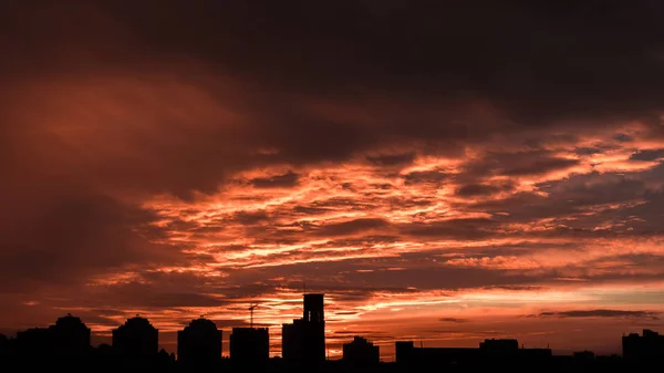 Sunset. Orange sky in the clouds. Silhouette of buildings.