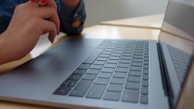 Bir kız kırmızı manikür ile bir dizüstü bilgisayarda metin yazma.