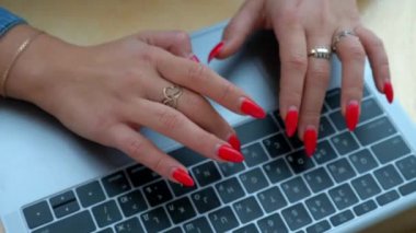 Bir kız kırmızı manikür ile bir dizüstü bilgisayarda metin yazma.