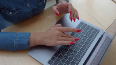 Bir kız kırmızı manikür ile bir dizüstü bilgisayarda metin yazma.