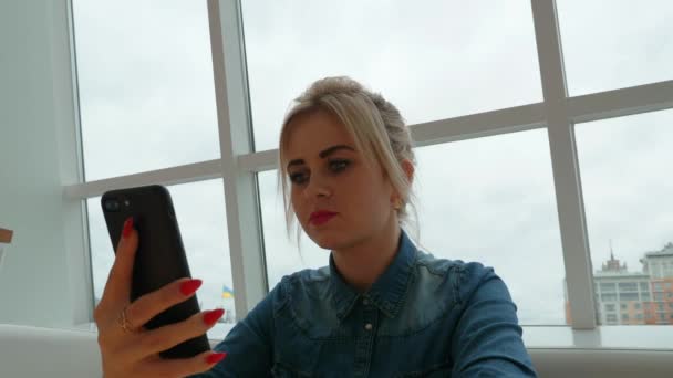 Une fille dans un café regarde dans un smartphone. Travailler sur le smartphone .