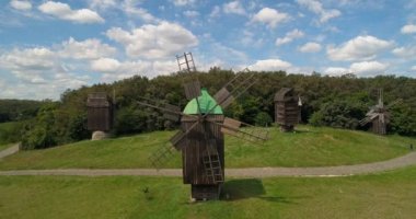 Arka planda yeşil ağaçlar ve çok güzel mavi gök, güneş, yaz hava görünümünü ahşap değirmenin. Halk Ulusal Müzesi mimari ve yaşam Ukrayna, Pirogovo. Drone uçuş 4k görüntüleri