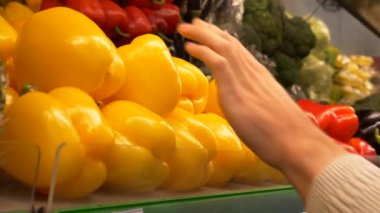 Genç adam sarı dolmalık biber süpermarkette seçer. El sarı biber sayaç deposuna alır. Sağlıklı gıda. 4 k görüntüleri