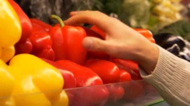 Genç adam kırmızı dolmalık biber süpermarkette seçer. El kırmızı biber sayaç deposuna alır. Sağlıklı gıda. 4 k görüntüleri