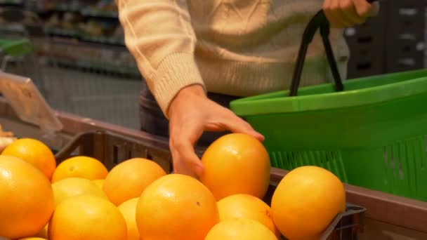 若い男は スーパー マーケットでオレンジを拾って 手が食料品グリーン バスケットのオレンジを入れます 健康食品 フルーツ 柑橘類 新鮮です — ストック動画