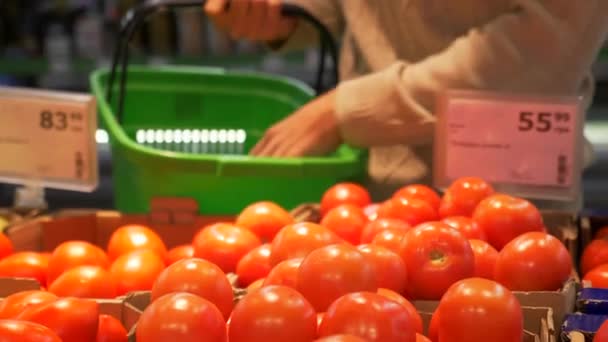 若い男は スーパーでトマトを選択します 手はカウンターから赤いトマトを緑のバスケットにそれを置きます 食料品店 健康食品 — ストック動画