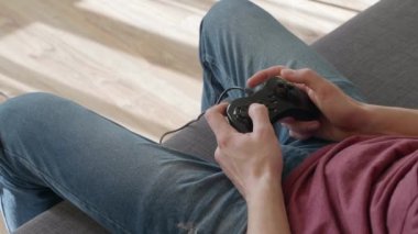 Kanepede oturan adam ve video oyunu oynamak. Genç adam gamepad'deki düğmelere basıyor. Close. 4k görüntü.