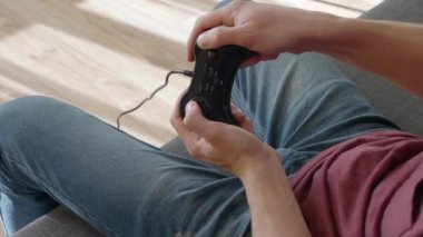 Kanepede oturan adam ve video oyunu oynamak. Genç adam gamepad'deki düğmelere basıyor. Close. 4k görüntü.