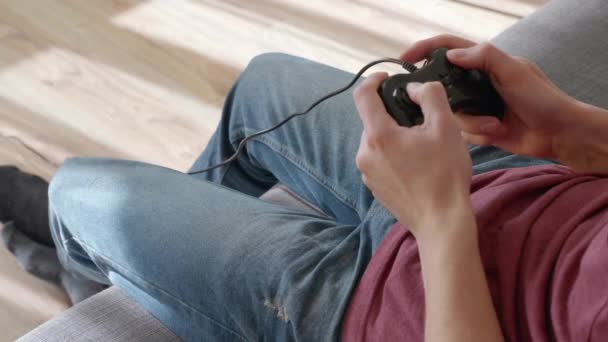 ソファに座って緊張してビデオゲームをする男 若い男は負け 怒りでゲームパッドを投げる クローズ アップ 4Kフッテージ — ストック動画