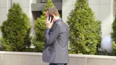Genç bir işadamı sokakta yürürken agresif bir telefon görüşmesi bir tartışma yol açar. Klasik takım elbiseli adam akıllı telefonda konuşarak öfkegösteriyor. 4k görüntü.