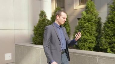 Genç bir işadamı sokakta yürürken agresif görüntülü arama bir tartışma yol açar. Klasik takım elbiseli adam video konferansında konuşarak öfkegösteriyor. 4k görüntü.