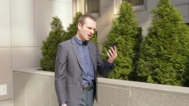 Genç bir işadamı sokakta yürürken agresif görüntülü arama bir tartışma yol açar. Klasik takım elbiseli adam video konferansında konuşarak öfkegösteriyor. 4k görüntü.