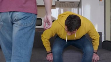 İki adam kanepede oturuyor ve bir futbol maçı izlemeye başlıyorlar. Genç bir adam, Tv uzaktan kumanda alır istenilen kanalı bulur ve arkadaşı ile favori programı izlemeye başlar. 4k görüntü.