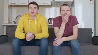 İki adam kanepede oturup Televizyonda bir futbol maçı izlemek beklentisiyle. 4k görüntü.