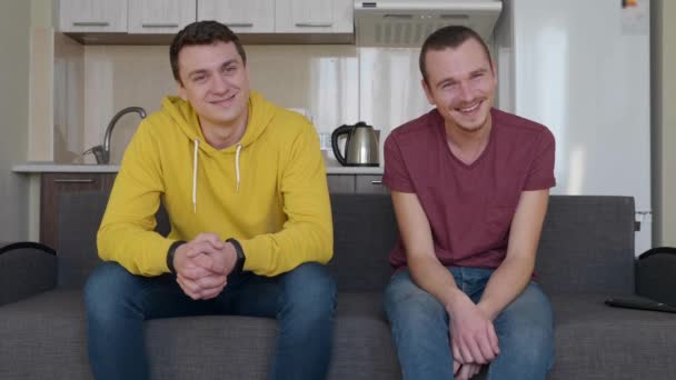Два Чоловіки Розмовляють Посміхаються Молоді Смішні Хлопці Сидять Дивані Сміються — стокове відео