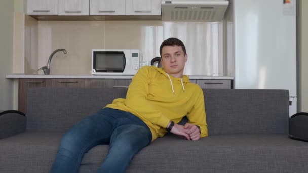 Hombre Descansa Sofá Joven Sentado Sofá Tosiendo Hablando Una Cocina — Vídeo de stock