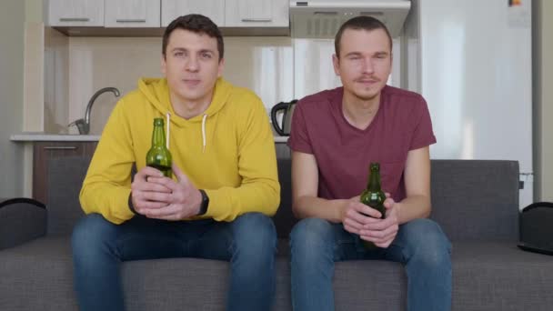 Dos Hombres Sentados Sofá Viendo Partido Fútbol Televisión Sosteniendo Botellas — Vídeo de stock