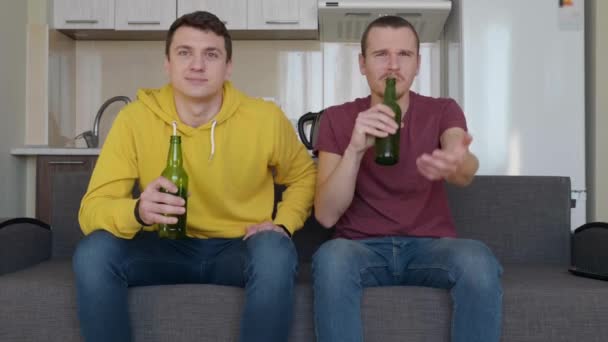 Dois Homens Sentados Sofá Assistem Jogo Futebol Bebem Cerveja Comentam — Vídeo de Stock