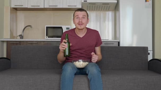 Hombre Viendo Partido Fútbol Tele Joven Sentado Sofá Bebiendo Cerveza — Vídeo de stock