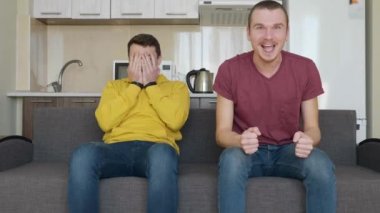 Kanepede oturan iki adam televizyonda bir futbol maçı izlemek ve farklı takımlara destek. Sevincini kazanan takımı destekleyen adam ve kaybeden takımın hayranı olan arkadaşı, elleriyle yüzünü kapatıyor..