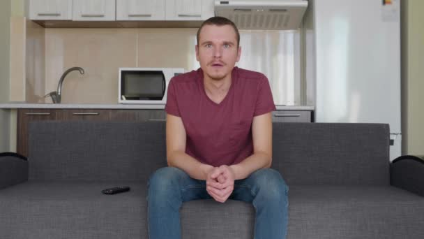 Mężczyzna Ogląda Telewizję Młody Facet Siedzi Kanapie Otwierając Usta Zaskoczeniu — Wideo stockowe