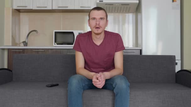 Mężczyzna Ogląda Telewizję Młody Facet Siedzi Kanapie Otwierając Usta Zaskoczenia — Wideo stockowe