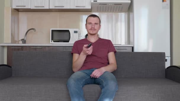 Hombre Está Viendo Televisión Joven Aburrido Sentado Sofá Sosteniendo Mando — Vídeos de Stock