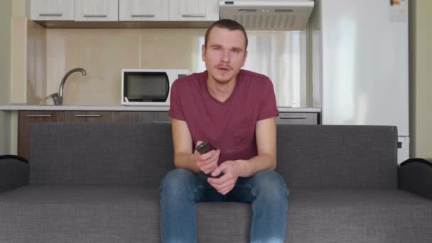 Jeune Homme Est Assis Sur Canapé Changer Chaîne Télé Bâiller — Video