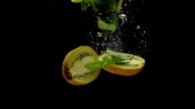 Kivi yarıya ve nane yaprakları siyah arka plan üzerinde şeffaf suya düşen. Akvaryumda sıçrayan taze meyveler ve meyveler. Organik meyve, sağlıklı yiyecekler, diyet, hava kabarcıkları. Yavaş Çekim. Close.