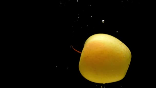 黒い背景に透明な水に落ちる1つの黄色いリンゴ 水族館で飛び散る新鮮な果物やベリー 有機果物 健康食品 ダイエット スローモーション クローズ アップ — ストック動画