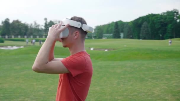 Een Man Zet Een Headset Zijn Hoofd Een Park Kijkt — Stockvideo