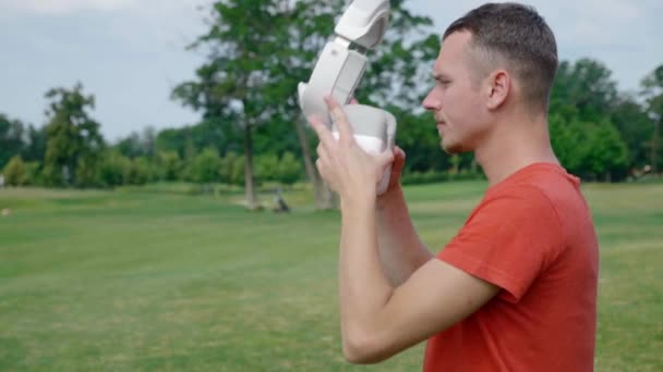 Hombre Pone Auricular Cabeza Parque Joven Con Una Camiseta Roja — Vídeos de Stock