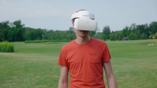 Человек Использующий Гарнитуру Виртуальной Реальности Парке Поворачивающий Голову Вниз Молодой — стоковое видео