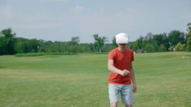 Bir adam VR kulaklık kullanarak ve parkta sanal bir oyun oynuyor. Kask genç adam doğanın arka planda artırılmış gerçeklik yaşıyor. Doğru çerçevede bir insan. 4k görüntüleri.