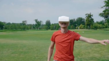 Bir adam VR kulaklık kullanarak ve parkta sanal bir oyun oynuyor. Kask genç adam doğanın arka planda artırılmış gerçeklik yaşıyor. Doğru çerçevede bir insan. 4k görüntüleri.