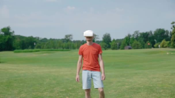 一个在公园里使用Vr耳机的男人回来了 面带微笑 头戴头盔的年轻人在自然背景中体验虚拟现实 框架中心的人 — 图库视频影像