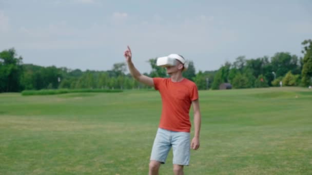 一个人使用Vr耳机 在公园里玩虚拟游戏 头戴头盔的年轻人在自然背景中体验增强现实 框架中心的人 — 图库视频影像