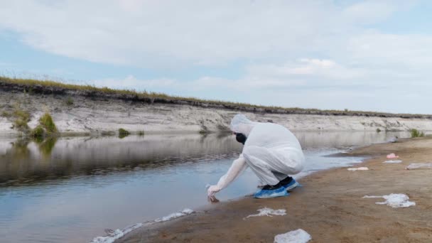 身着防护服和呼吸器防毒面具的男子观察试管中水的化学反应 他从一条被污染的河流湖中进行分析 科学家在体外取样 — 图库视频影像