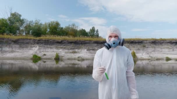 Ein Mann Schutzanzug Und Gasmaske Steht Mit Einem Reagenzglas Der — Stockvideo